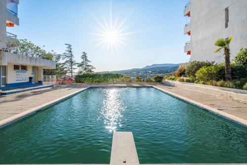 une piscine d'eau en face d'un bâtiment dans l'établissement Les 3 Caravelles par Dodo à Cassis, à Cassis