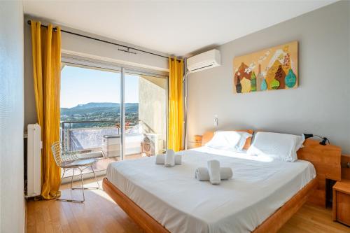 une chambre avec un grand lit et une grande fenêtre dans l'établissement Les 3 Caravelles par Dodo à Cassis, à Cassis