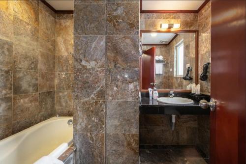 a bathroom with a tub and a sink and a mirror at A25 Hotel - 221 Bạch Mai in Hanoi