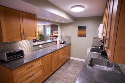 a kitchen with wooden cabinets and a sink at Awesome 2BR in Lynn Valley in North Vancouver