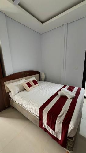 a bedroom with a bed with a red and white blanket at Mandhasativa Homestay in Singaraja