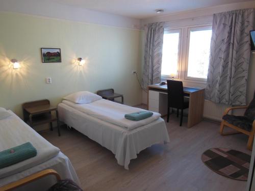 a hotel room with a bed and a desk and a window at Maalaiskartano Pihkala in Kestilä