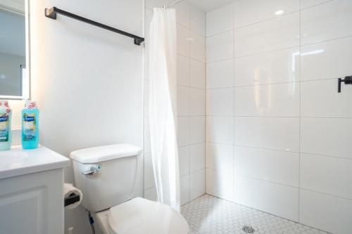 a white bathroom with a shower and a toilet at Stylish & Cozy Retreat Near USC & Downtown LA in Los Angeles