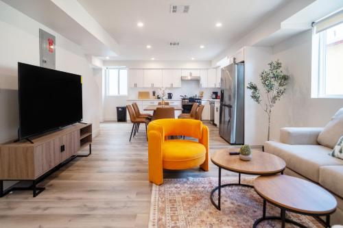 a living room with a tv and a yellow chair at Stylish & Cozy Retreat Near USC & Downtown LA in Los Angeles
