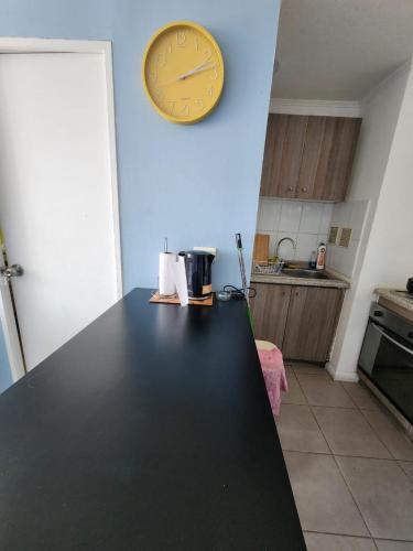 a kitchen with a clock on the wall and a counter at Departamento en Quinta Normal in Santiago