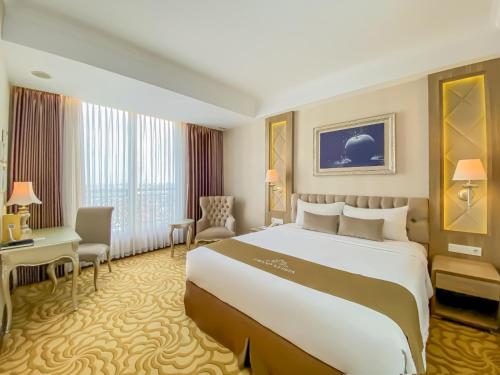 a hotel room with a large bed and a desk at Grand Keisha Yogyakarta in Yogyakarta