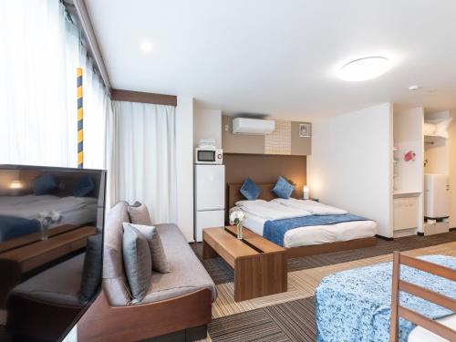 a hotel room with two beds and a couch at Tabist Sakuragawa River Side Hotel in Osaka