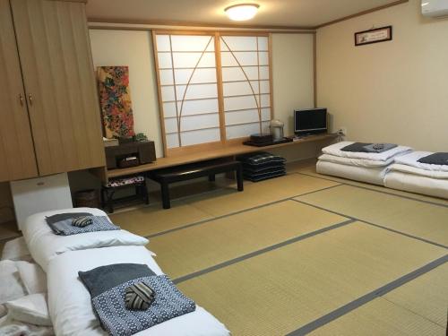 een kamer met 2 bedden en een televisie. bij Tamaki Ryokan in Kumamoto
