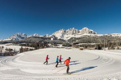 a group of people skiing down a snow covered slope at Landhaus Wöss in Ellmau