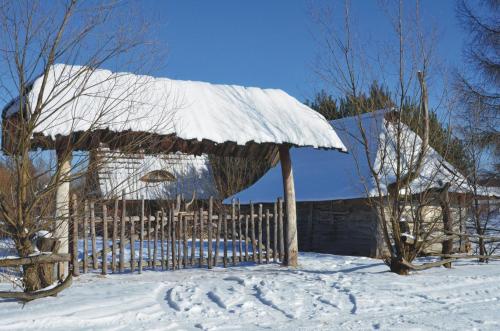 a barn with snow on the roof of it at Domki Osada Werdołyna in Polańczyk