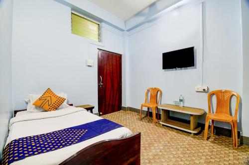 a bedroom with a bed and a table and a tv at Hotel O NANDINI in Dibrugarh