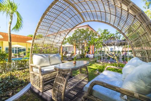 an arbor over a patio with a table and chairs at Tongtong Garden Holiday Hotel普吉岛通通花园酒店 in Rawai Beach