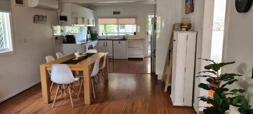 a kitchen with a wooden table and white appliances at Cottage on Clare in Batehaven