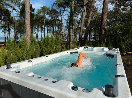a person in a jacuzzi in a pool at Maison du Lac avec Lagon, Spa de Nage, Jacuzzi in Biscarrosse