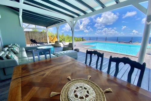Un comedor con mesa y una piscina. en Villa Horizon, en Grand-Bourg