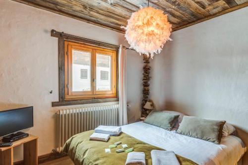 - une chambre avec un lit, une télévision et un lustre dans l'établissement Appartement Amédé - Welkeys, à Megève