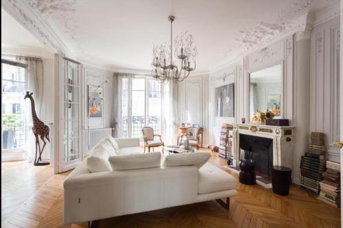 un salon avec un canapé blanc et une cheminée dans l'établissement Appartement Pétrarque - Welkeys, à Paris