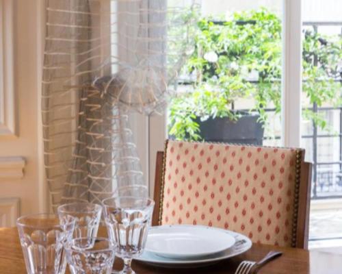 une table en bois avec une assiette et des verres dans l'établissement Appartement Pétrarque - Welkeys, à Paris