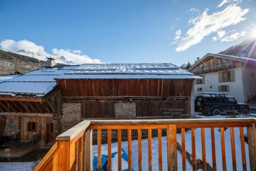 une terrasse en bois avec de la neige sur le toit d'un bâtiment dans l'établissement Chalet Mil, à Les Allues