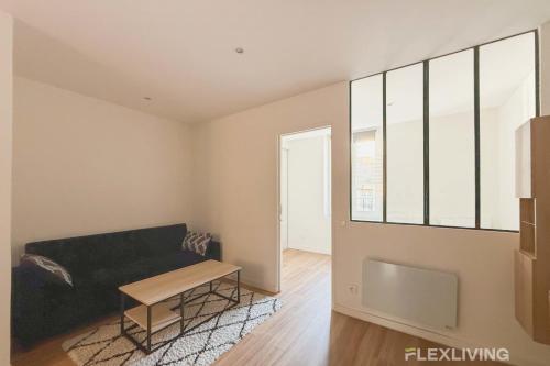 un salon avec un canapé et une table dans l'établissement Flexliving - T2 - Montreuil, à Paris