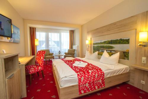 a hotel room with a bed with a red blanket on it at Falk Seehotel Plau am See in Plau am See
