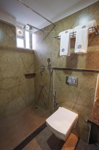 a bathroom with a shower and a toilet and towels at Vaishnavi Residency in Bengaluru