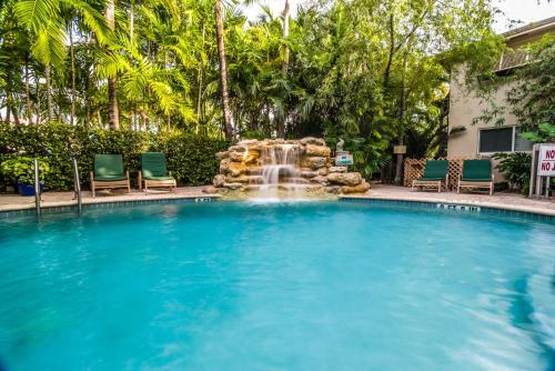einen Pool mit einem Wasserfall und grünen Stühlen in der Unterkunft Crane's Beach House Boutique Hotel & Luxury Villas in Delray Beach