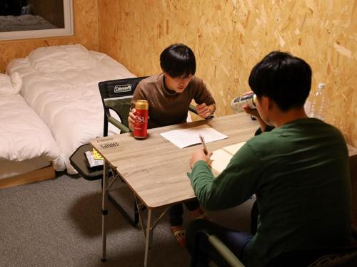 a couple of men sitting at a table at ＳＡＫＡＴＡＮＴＯ Ｃｏｎｔａｉｎｅｒ Ｈｏｔｅｌ ＣＡＭＰＳ - Vacation STAY 93094v in Sakata