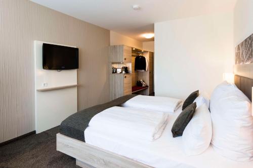 a hotel room with a bed and a tv at Best Western Plus Parkhotel Velbert in Velbert