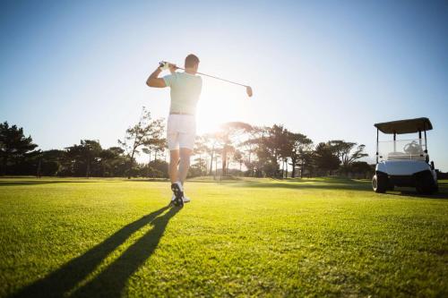 a man swinging a golf club on a golf course at Best Western Plus Parkhotel Velbert in Velbert