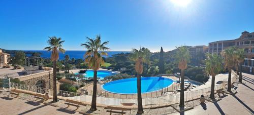 Elle offre une vue sur la piscine bordée de palmiers et l'océan. dans l'établissement Cap Estérel-T2-Clim-Vue Mer, à Saint-Raphaël