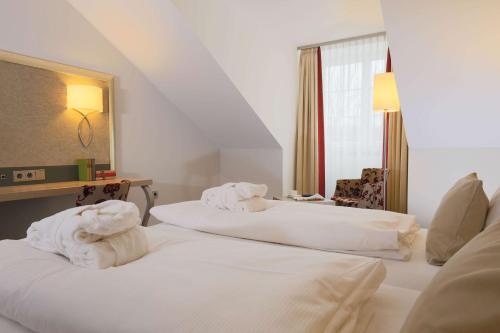 a hotel room with two beds with towels on them at Hotel Bayerischer Hof Miesbach, BW Premier Collection in Miesbach
