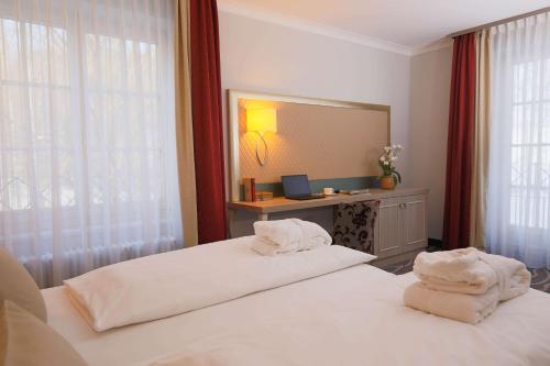 two beds in a hotel room with towels at Hotel Bayerischer Hof Miesbach, BW Premier Collection in Miesbach