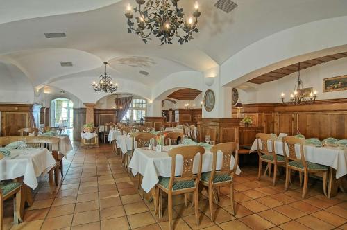 a restaurant with white tables and chairs and a chandelier at Hotel Bayerischer Hof Miesbach, BW Premier Collection in Miesbach