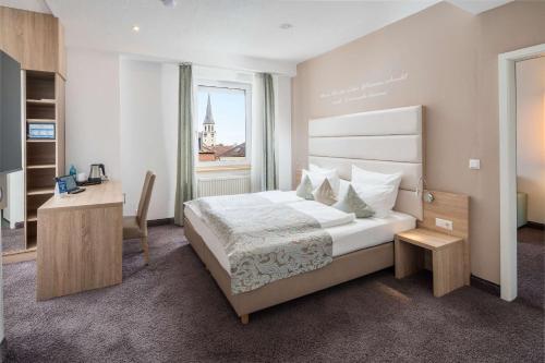 a bedroom with a bed and a desk and a window at Best Western Hotel Lamm in Singen