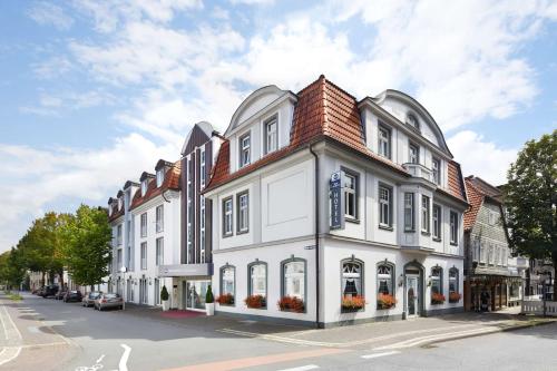 a white building with a red roof on a street at Best Western Hotel Lippstadt in Lippstadt