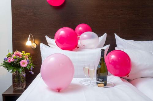 a bottle of champagne and balloons on a bed at Best Western Hotel am Spittelmarkt in Berlin