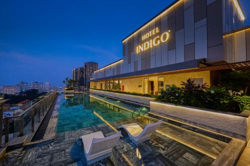 胡志明市Hotel Indigo Saigon the City by IHG的一座大楼前的游泳池,配有两把椅子