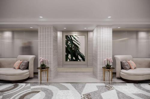 a lobby with two white chairs and a mirror at Waldorf Astoria New York in New York