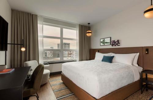 a hotel room with a bed and a desk and a window at Kissel Uptown Oakland, in the Unbound Collection by Hyatt in Oakland