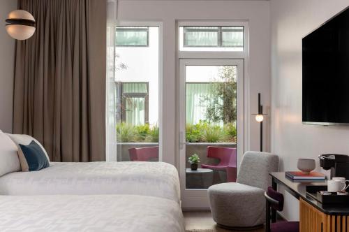 a hotel room with a bed and a chair and a window at Kissel Uptown Oakland, in the Unbound Collection by Hyatt in Oakland