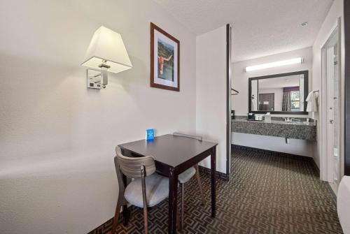 a hotel room with a table and a mirror at Days Inn by Wyndham Round Rock in Round Rock