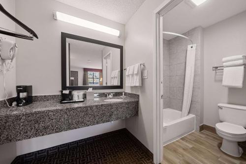 a bathroom with a sink and a toilet and a mirror at Days Inn by Wyndham Round Rock in Round Rock
