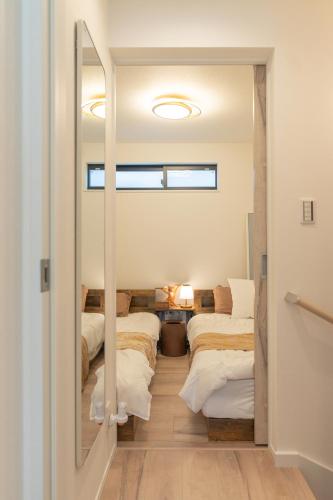 a room with four beds and a mirror at RIAUS 新築一軒家貸切 最大6名 family歓迎 空港や観光地直通 in Tokyo