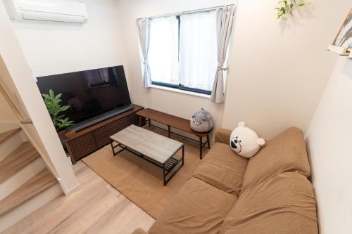 a living room with a couch and a television at RIAUS 新築一軒家貸切 最大6名 family歓迎 空港や観光地直通 in Tokyo