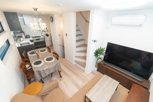 a living room with a table and a large television at RIAUS 新築一軒家貸切 最大6名 family歓迎 空港や観光地直通 in Tokyo