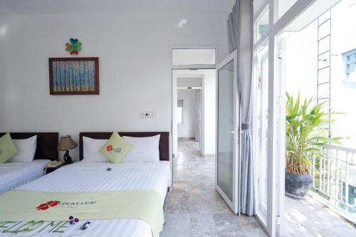 a bedroom with two beds and a balcony at Lucky Leaf Hoian Villa in Hoi An