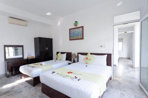 two beds in a room with white walls at Lucky Leaf Hoian Villa in Hoi An