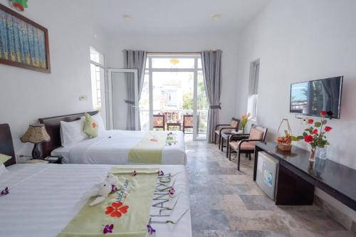 a hotel room with two beds and a television at Lucky Leaf Hoian Villa in Hoi An