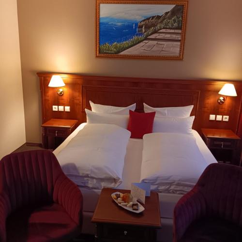 a hotel room with a bed and two chairs at Schwarzwaldhotel Sonne in Baden-Baden